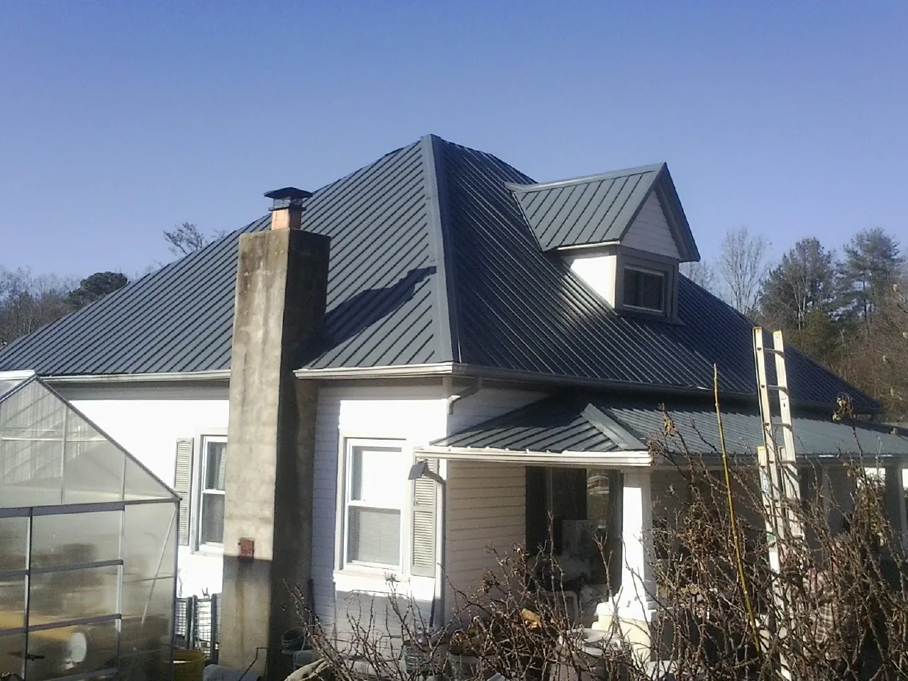 Dark blue standing seam metal roof on a white farmhouse with dormer — Slate & Tile Roof Repair by Roofing Brothers in Hopedale