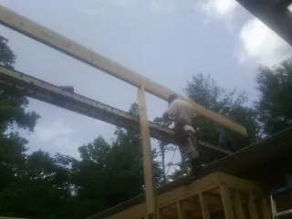 Carpenter setting a ridge beam over a new addition frame — Ice Dam Removal by Roofing Brothers in Hopedale