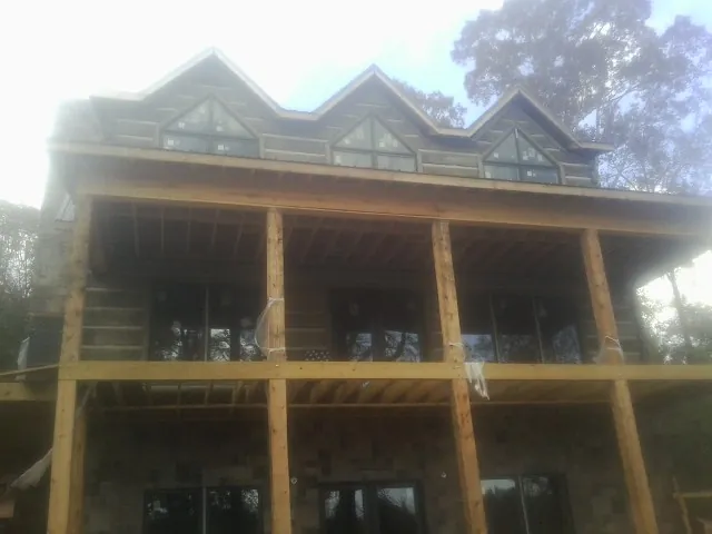 Dormers and porch framing on a large log home under construction — Roof Coating work by our crew in Hopedale