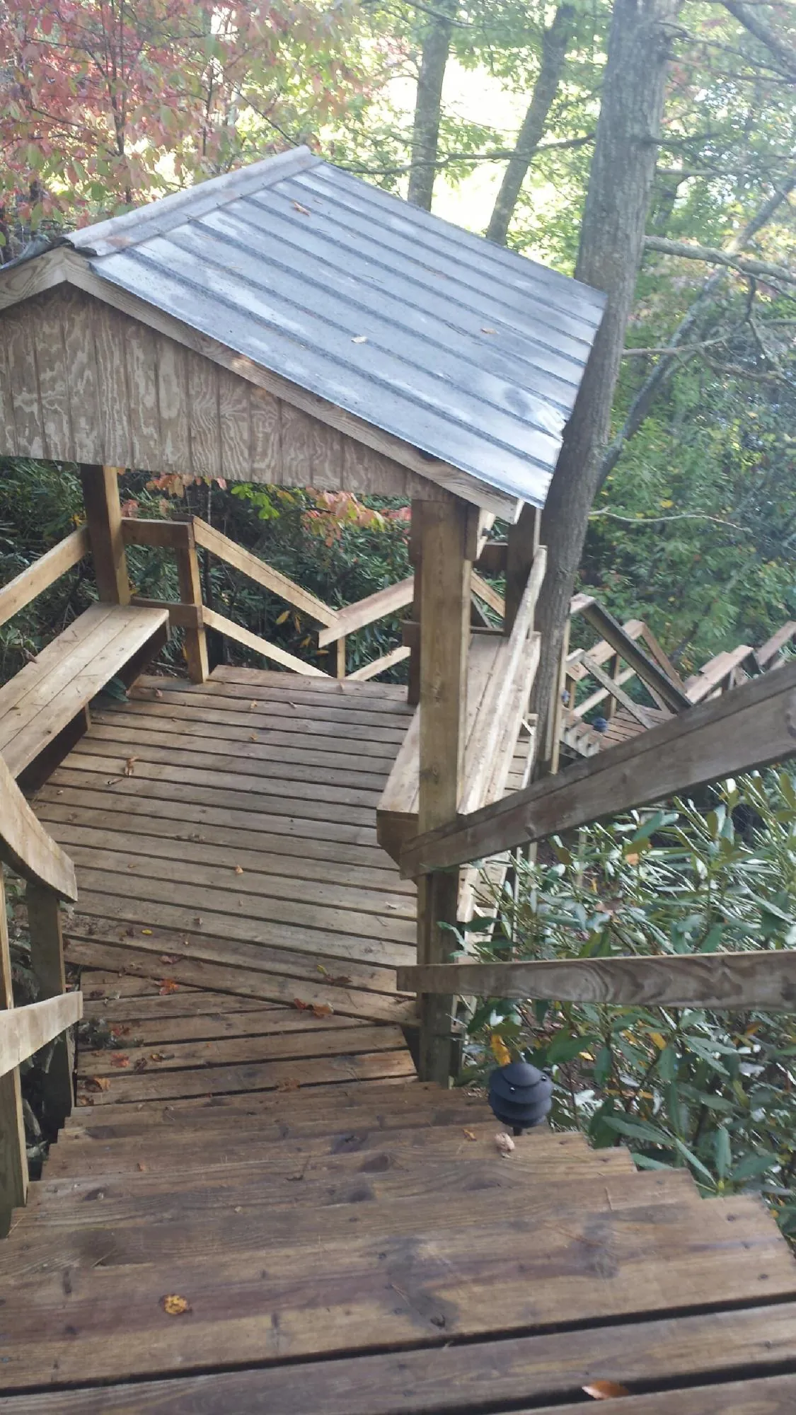 Metal roofed shelter over wooden steps on a wooded walkway — Skylight Repair & Installation work by our crew in Hopedale
